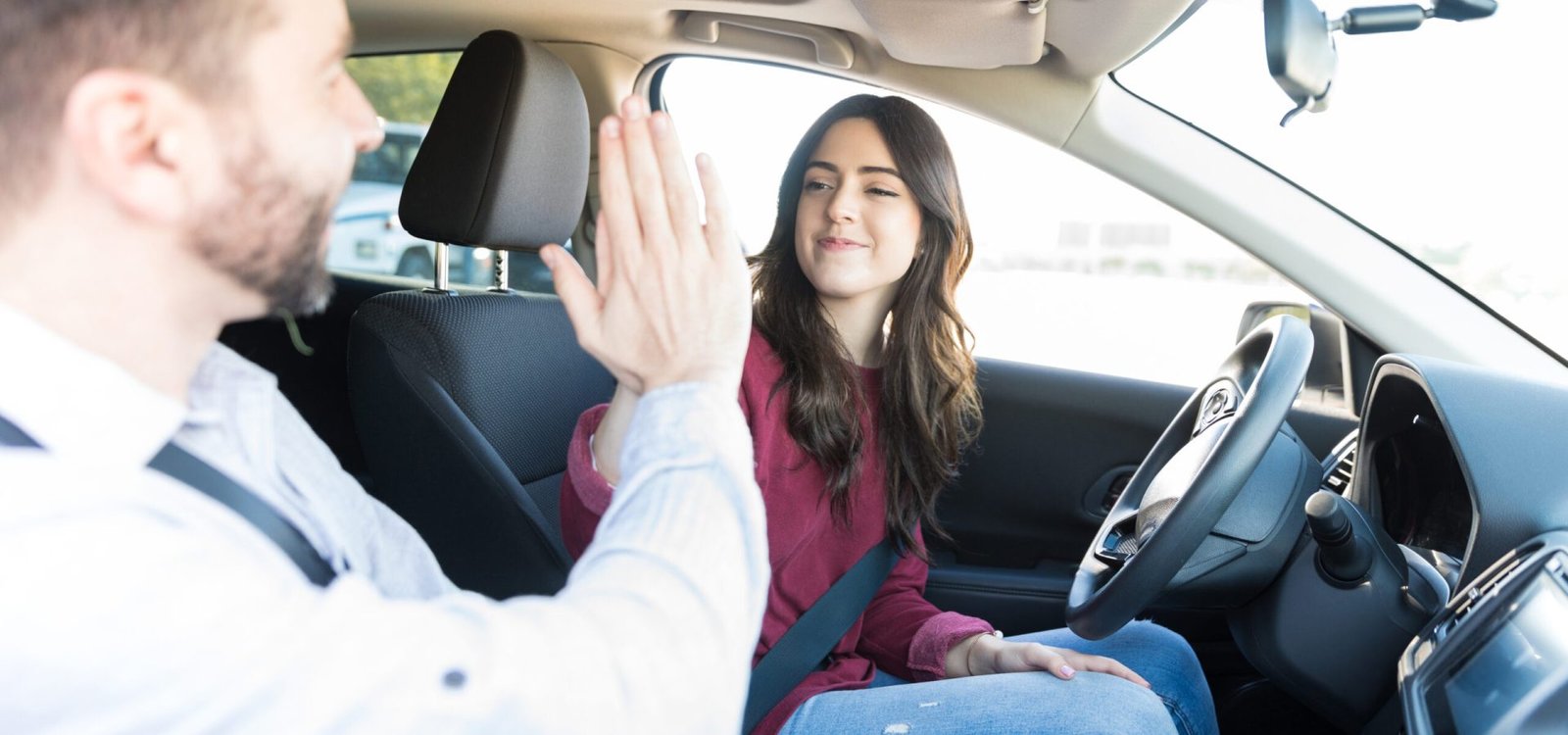Successful young woman giving high-five after passing car driving test