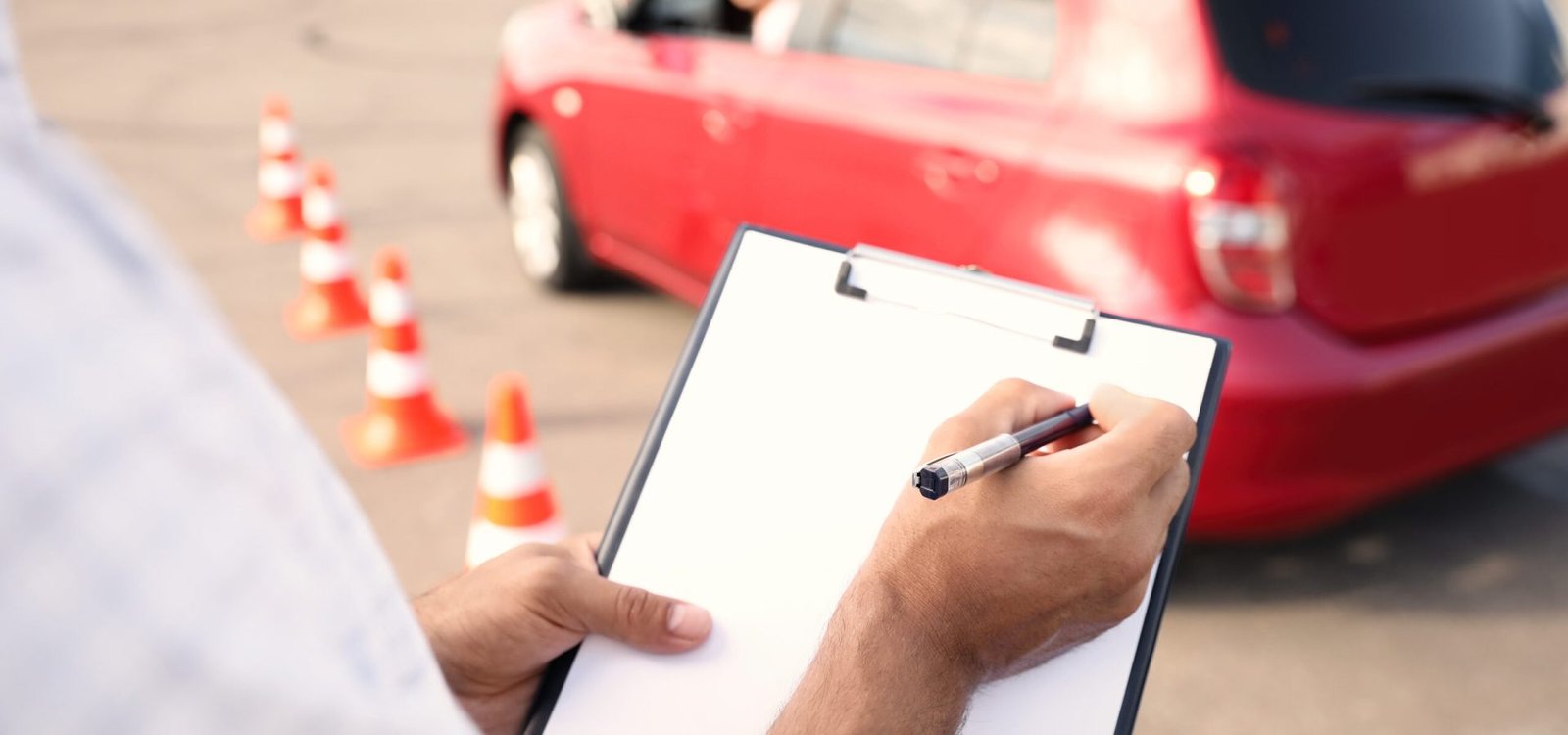 Instructor with clipboard near car outdoors, closeup. Driving school exam